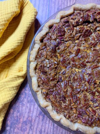 A Pecan Cheesecake Pie with a gold cloth napkin beside it.