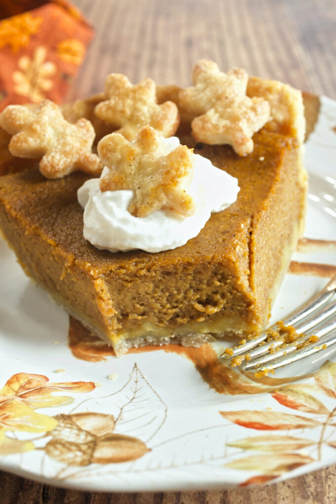 A slice of Perfect Pumpkin Pie on with pastry leaves and a dollop of whipped cream.