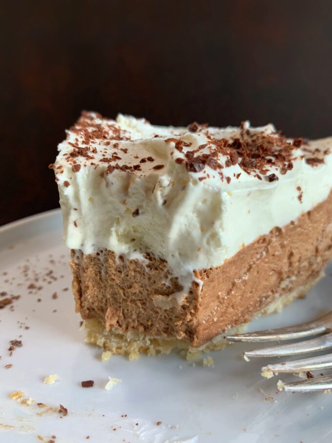 A slice of Chocolate Chiffon Pie topped with whipped cream and shaved chocolate.