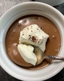 Chocolate Mousse with whipped cream in white ramekins.