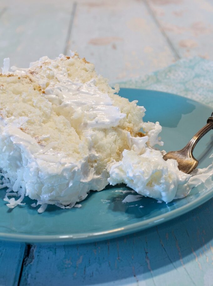 A slice of Coconut Cloud Cake on a blue plate.