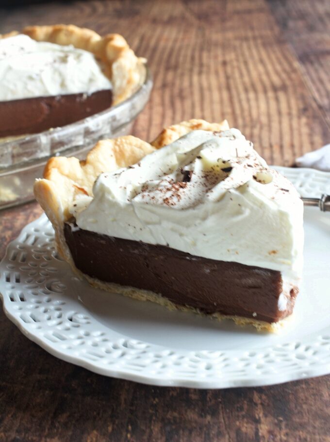 A slice of old fashioned chocolate cream pie with whipped cream on top.