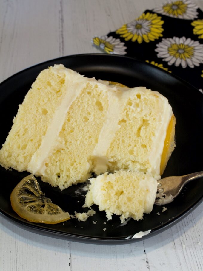 A slice of Lemon Layer Cake with a bite out of it.