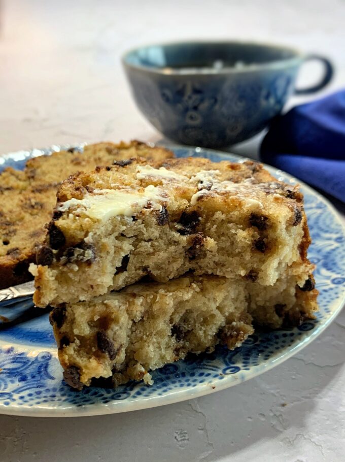 A slice of Chocolate Chip Banana Bread cut in half and slathered with butter.