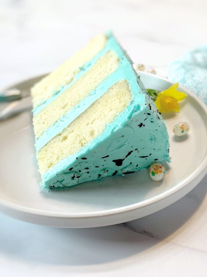 A slice of speckled Easter cake on a white plate.