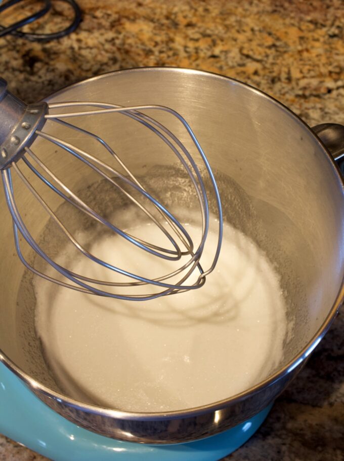 A mixing bowl full of simple syrup, egg white mixture getting ready to be beaten into meringue.