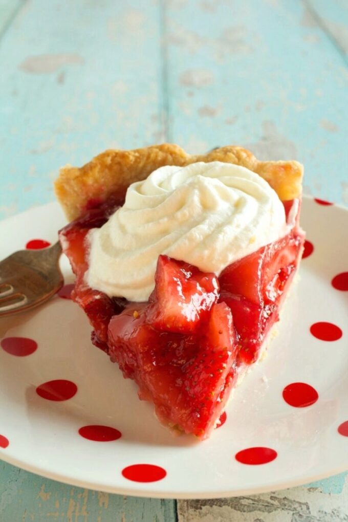 A slice of Strawberry Glaze Pie with whipped cream on top.