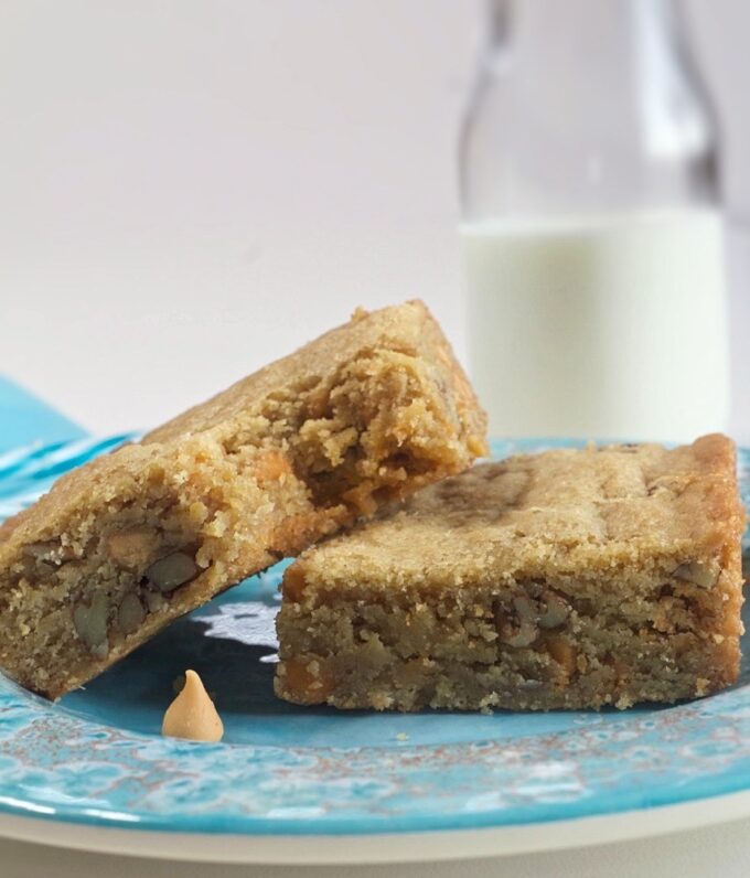 Butterscotch Pecan Blondies on a plate with a glass of milk.