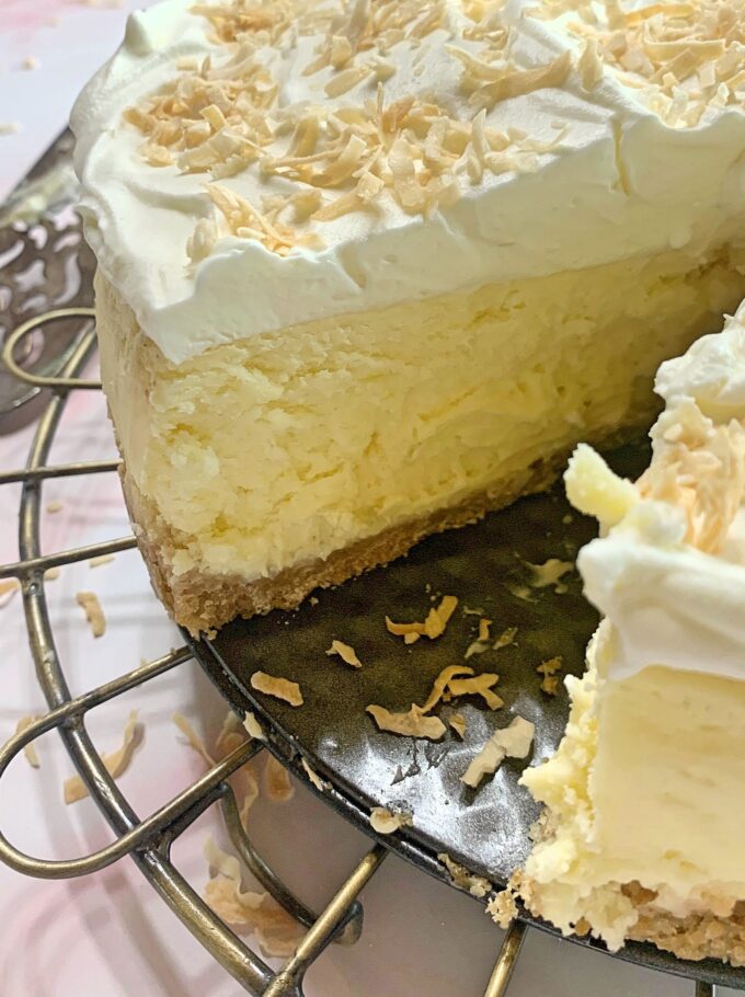 A Coconut White Chocolate Cheesecake with a slice out.