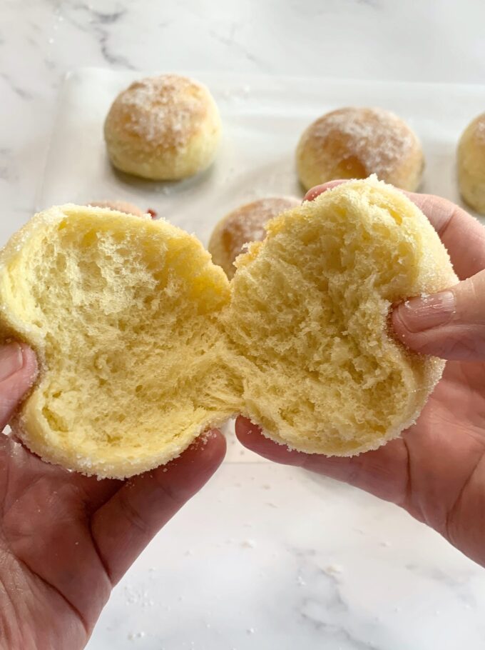 A baked jelly donut torn in half to show how fluffy and soft it is.