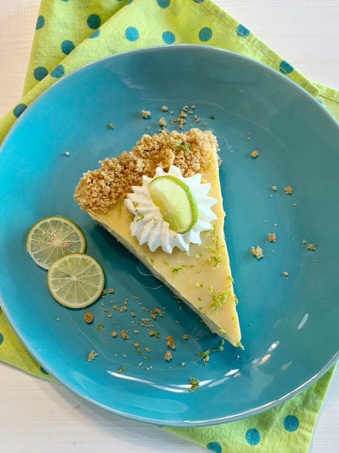 An overhead picture of a slice of Key Lime Pie on a blue dessert plate.