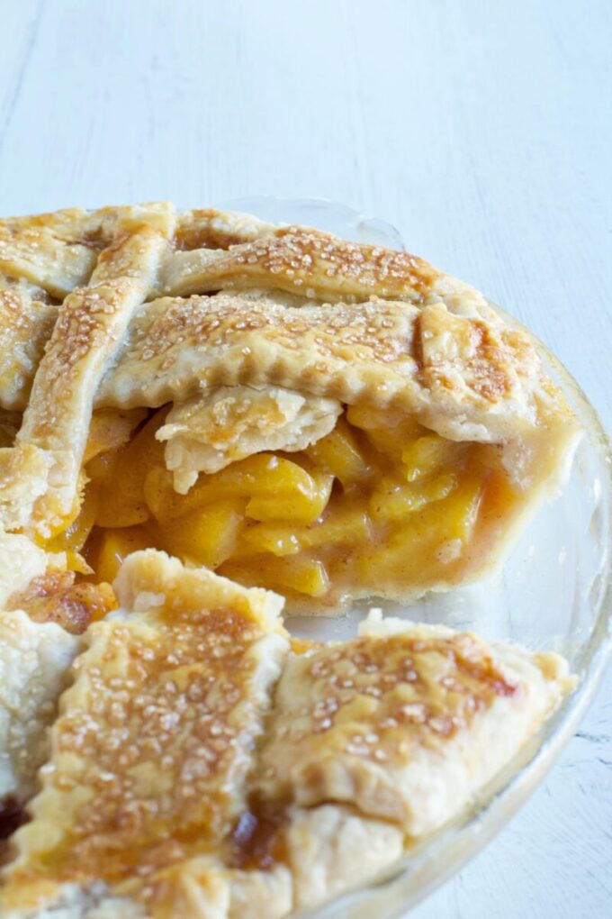 A lattice topped peach pie with a slice missing.