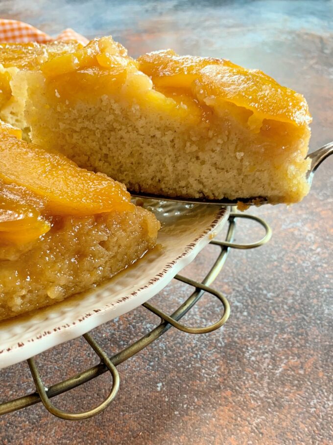 A peach upside down cake with a slice being removed.