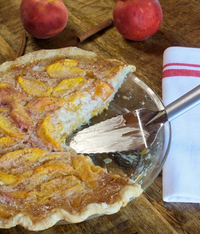 A peaches and cream pie with a missing slice.