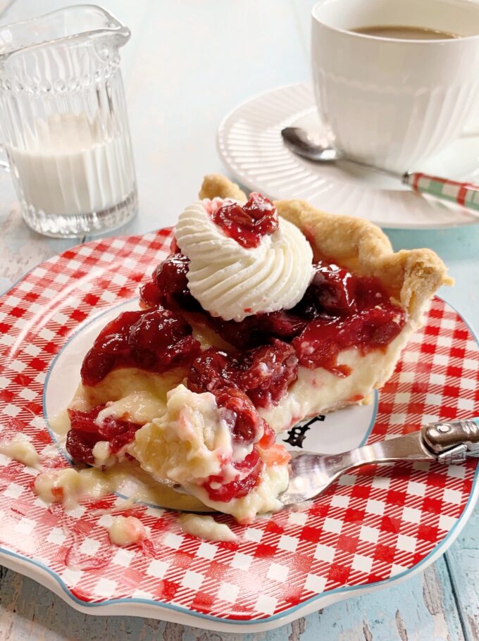 A slice of cherry cream pie with a forked bite.