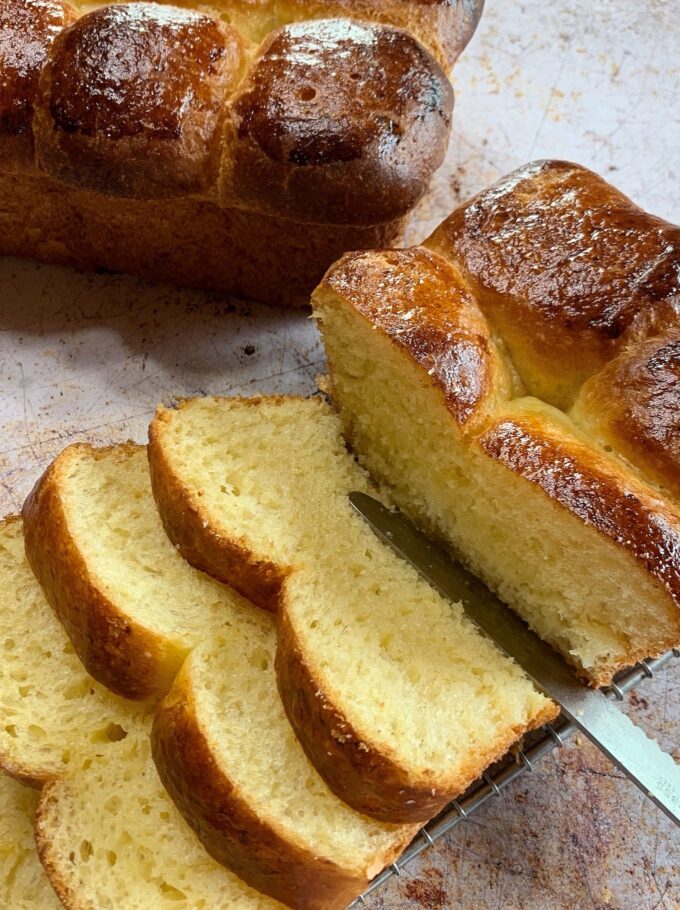 A partially sliced loaf of brioche bread.