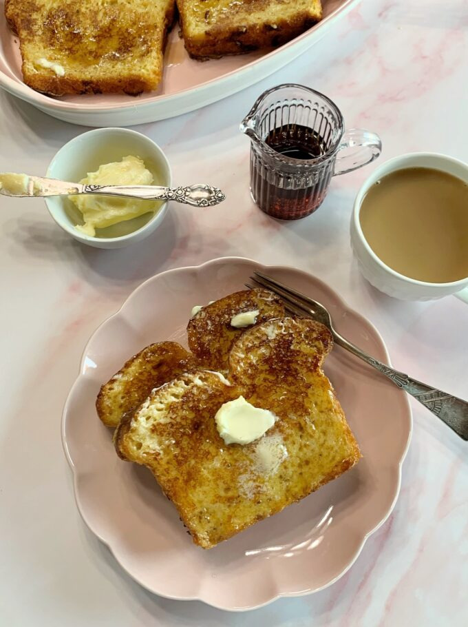 A plate with two slices of French toast with butter and syrup.