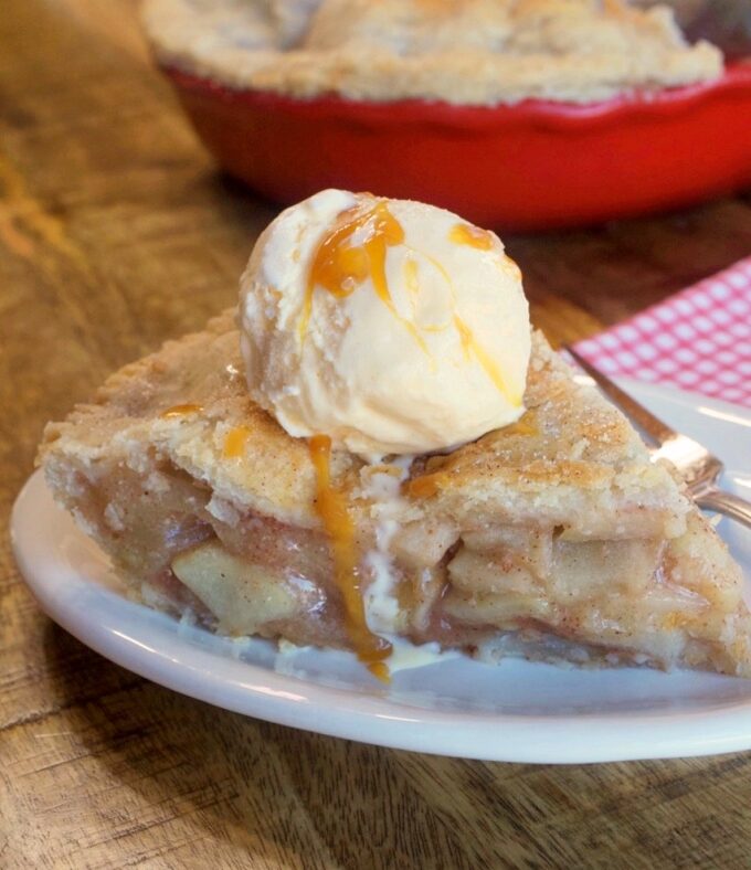 A slice of country apple pie topped with ice cream.