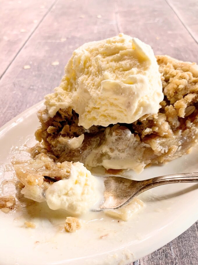 A slice of apple streusel pie with ice cream.